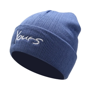 Detailed view of the blue knitted beanie featuring white 'Yours' letter embroidery