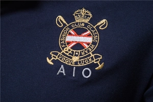 Macro detail of navy cotton piqué fabric and exquisite embroidered chest emblem on polo shirt