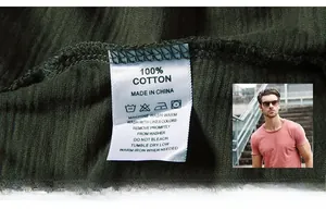 Close-up of 100% cotton washing label and textured knit fabric on dark green t-shirt