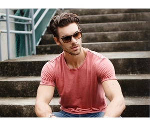 Outdoor lifestyle shot of a man wearing a slim fit cotton T-shirt and classic sunglasses