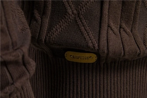 Macro detail of men's brown knit cardigan with leather logo patch and metal rivets