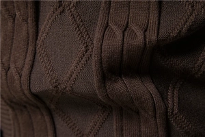 Macro shot of dark brown thick knit sweater with classic diamond and cable patterns