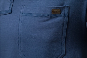 Detailed macro view of the chest pocket on a navy blue cotton T-shirt with metal tag