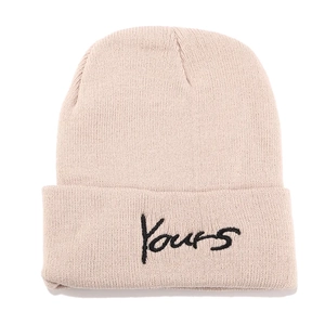 Close-up of beige knitted beanie featuring Yours letter embroidery and ribbed texture