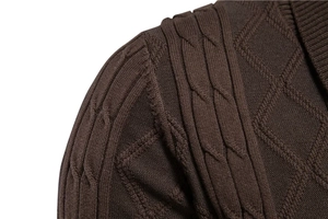 Macro shot of dark brown knit cardigan showing detailed cable stitch and shoulder seam