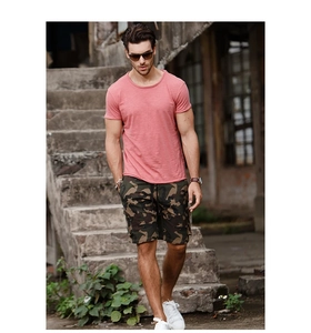 Outdoor street shot of a man wearing pink cotton t-shirt and camo cargo shorts