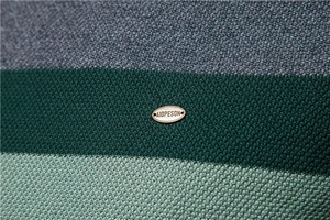 Detailed close-up of the striped knit fabric texture with a golden metal brand plate