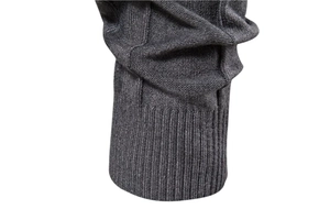 Detail of dark grey knit sweater showing ribbed cuffs and textured cotton fabric