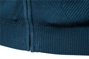 Vue macro du pull en maille bleu foncé montrant l'ourlet côtelé et la texture dense