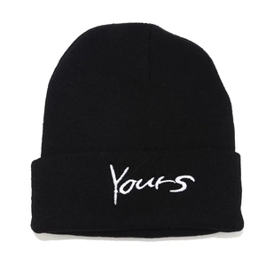Close-up of black knitted beanie featuring white Yours script embroidery and wool texture