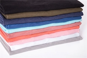 Close-up of stacked slub cotton t-shirts showing various colors and fabric textures