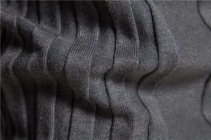 Macro shot of dark grey knit fabric showing detailed wave pattern on the sweater