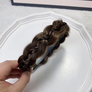 Detailed texture of dark brown braided fishtail headband on a white lace background