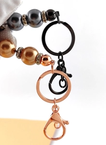 Detail of beaded keychains featuring faux pearls, rhinestone rings, and metal lobster clasps