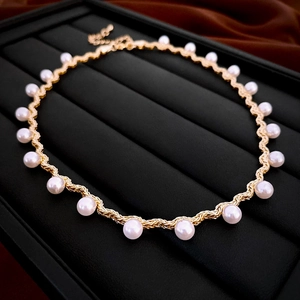Detail of gold twisted chain necklace with faux pearls on black jewelry display pad