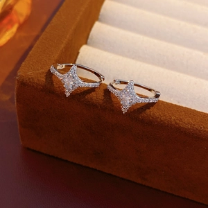 Detail of star-shaped silver hoop earrings with cubic zirconia on a brown velvet box
