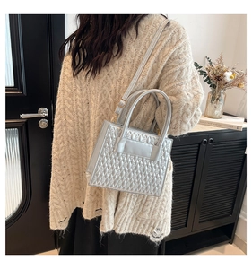 Detail of silver quilted tote bag featuring metallic finish and round handles