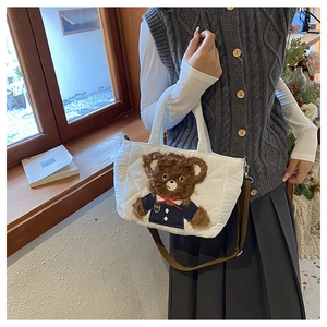 Detail of white quilted handbag with 3D teddy bear patch worn in a cozy indoor setting