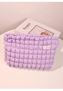 Detalle de neceser morado con textura de burbujas, cremallera y etiqueta de tela de marca