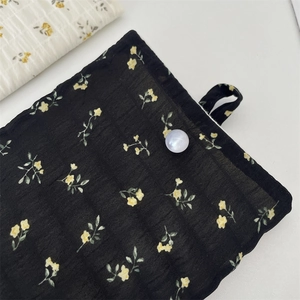 Détail de la pochette téléphone en mousseline fleurie avec bouton perle élégant