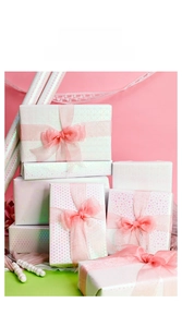 Close-up of pink glitter gift wrapping paper with heart patterns and silk ribbon bows