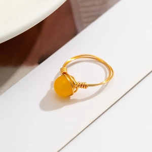 Detailed macro shot of handmade gold wire-wrapped ring with yellow cat-eye stone bead
