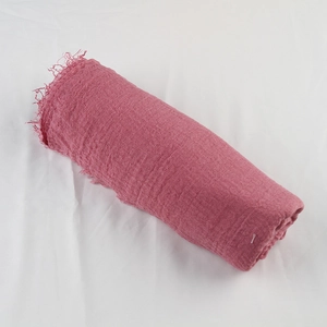 Detail shot of rose pink cotton linen scarf featuring wrinkled texture and raw fringed edges