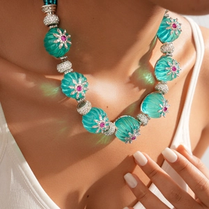 Close-up of a floral beaded necklace with turquoise melon beads and pink rhinestones