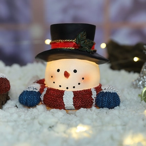 Cute resin snowman figurine with glowing light, winter Christmas holiday decor on snow