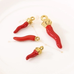 Detailed view of red chili pepper charms with gold-tone hardware on white ceramic plate