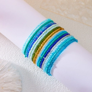 Close-up of stacked colorful gradient seed bead bracelets on a white support