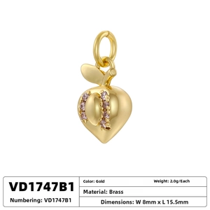 Detail of a gold peach fruit pendant with pink zircons on polished brass base