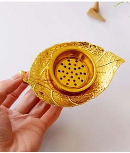 Macro view of gold leaf-shaped metal incense burner with detailed vein texture