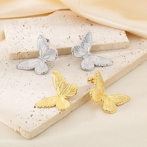 Detail showing gold and silver butterfly stud earrings on a textured stone surface
