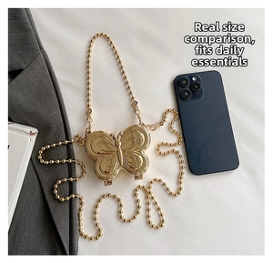 Detailed size comparison of the gold butterfly metal crossbody bag next to a smartphone