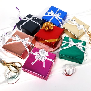 Matte aluminum gift wrapping paper rolls in multiple metallic colors on white silk background