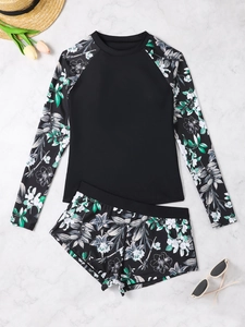 Flat lay of long sleeve floral rash guard and swim shorts on white marble background