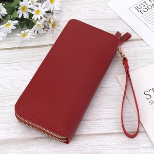 Detail of red long double zipper wallet with lychee grain texture and wrist strap