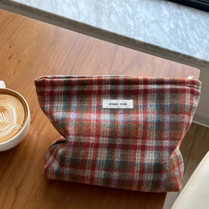Plaid wool fabric cosmetic bag with 'simple wish' tag on a cozy wooden tabletop