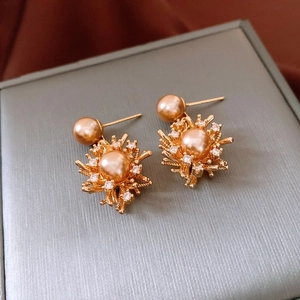 Detail of 18K gold-plated firework earrings with pearls and zircon stones on a jewelry box