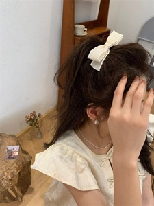 Eleganter cremeweißer Satin-Haarclip mit Schleife und Perlenbesatz an einem Model
