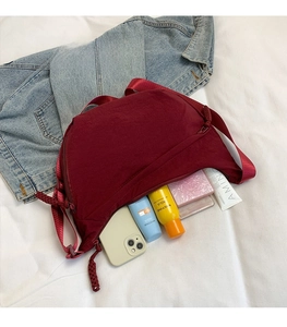 Spacious burgundy crescent nylon bag showing interior storage for phone and cosmetics