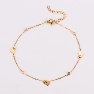 Golden ankle bracelet with heart charms and crystal rings on a clean white background