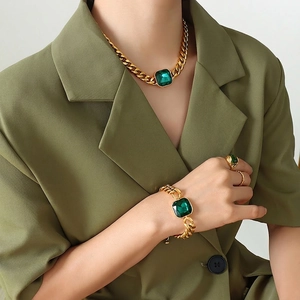 Gold plated chunky jewelry set with emerald green stones on model with green suit