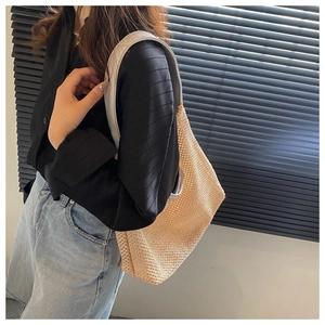 Close-up of beige woven beach shoulder bag with white strap on female model
