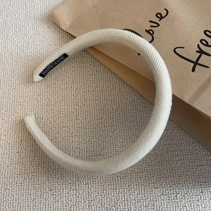 Close-up of beige ribbed knit headband featuring a small black handmade tag detail