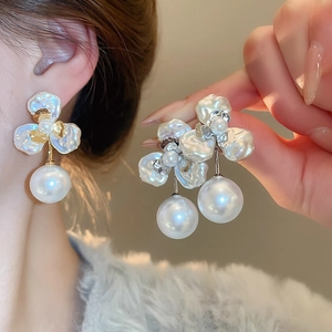 Detail of petal-shaped gold-plated stud earring featuring a large round white pearl