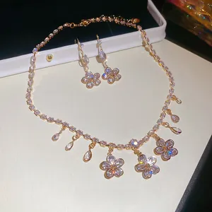 Detailed macro view of gold-plated flower necklace and earrings with zircon fringe drops