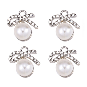Detailed view of four silver bow pendants with clear rhinestones and large white pearls