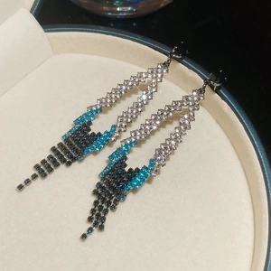 Détail macro de boucles d'oreilles géométriques à glands avec cristaux bleus et clairs